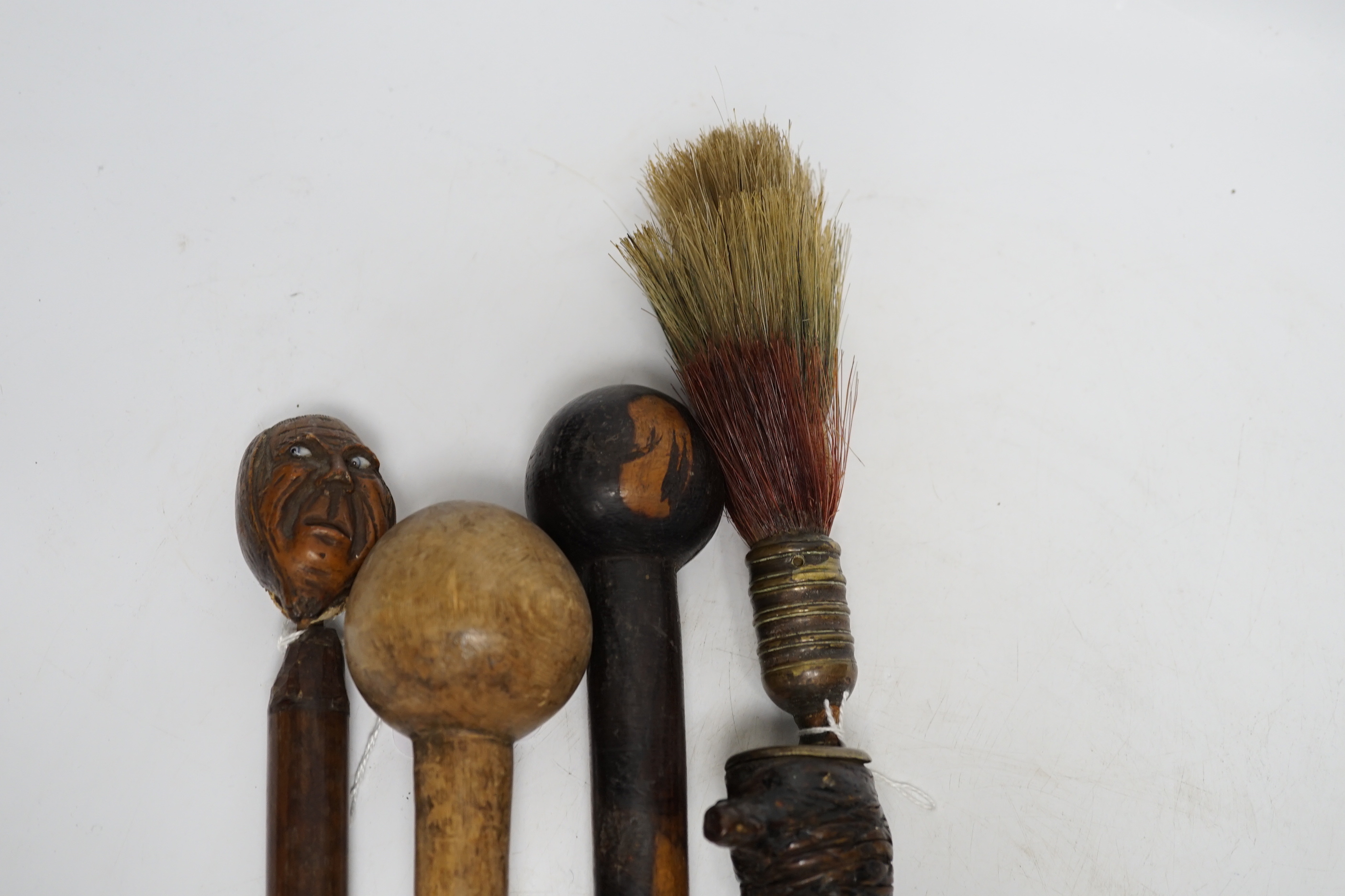 A ceremonial sword stick with removable brush end, a 19th century continental carved head with glass eyes on associated cane stick and two others, longest 93cm